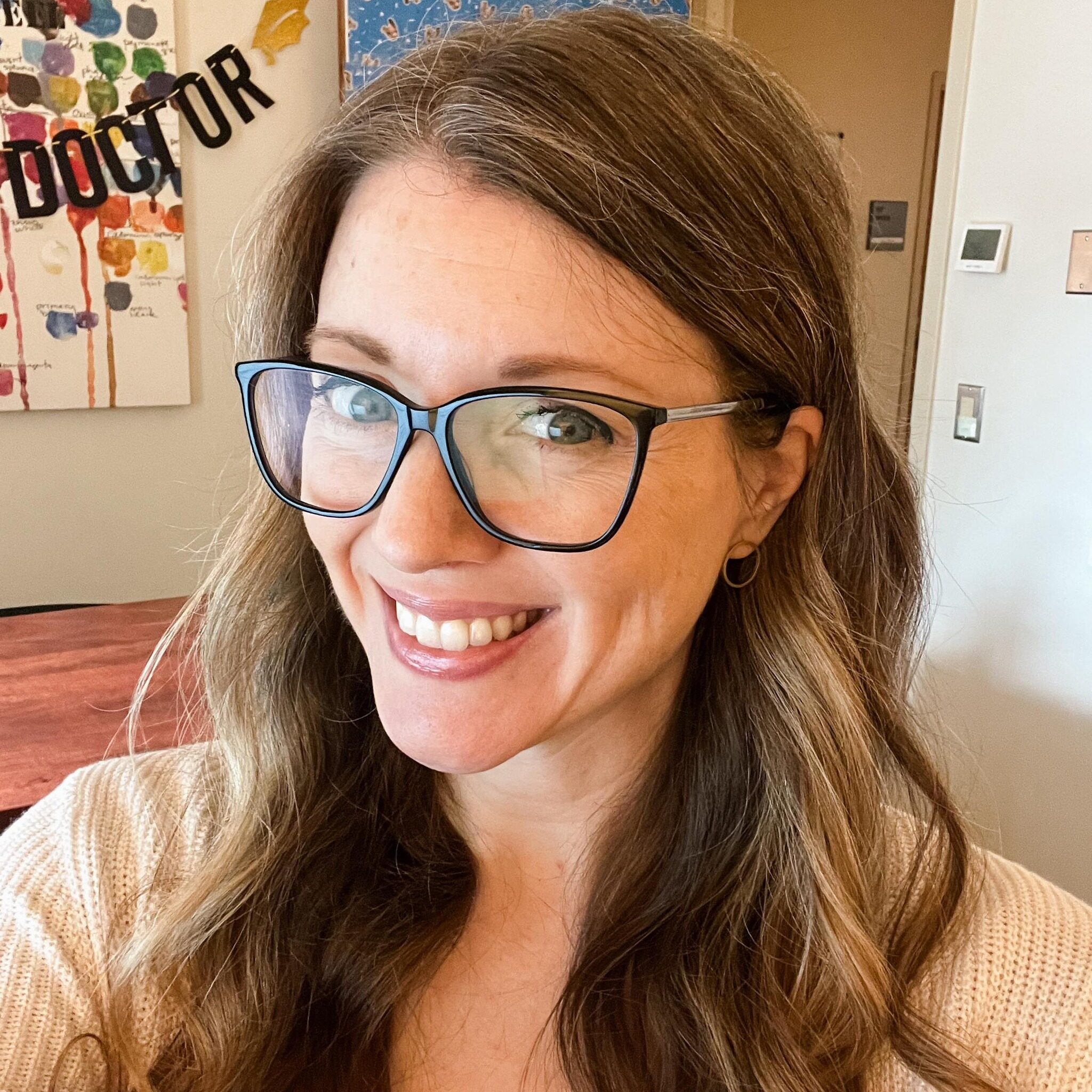 photo of Angie wearing glasses in front of a sign that says doctor in the background