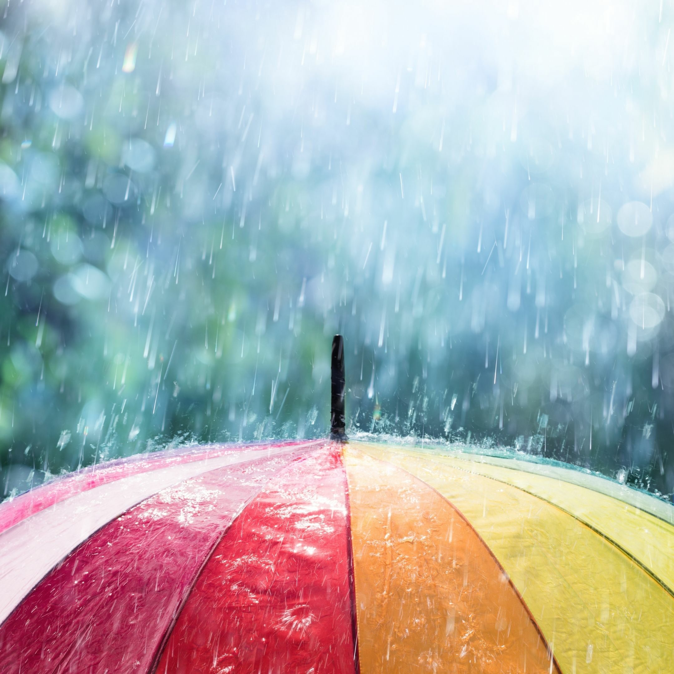 Colorful umbrella with rain falling on top
