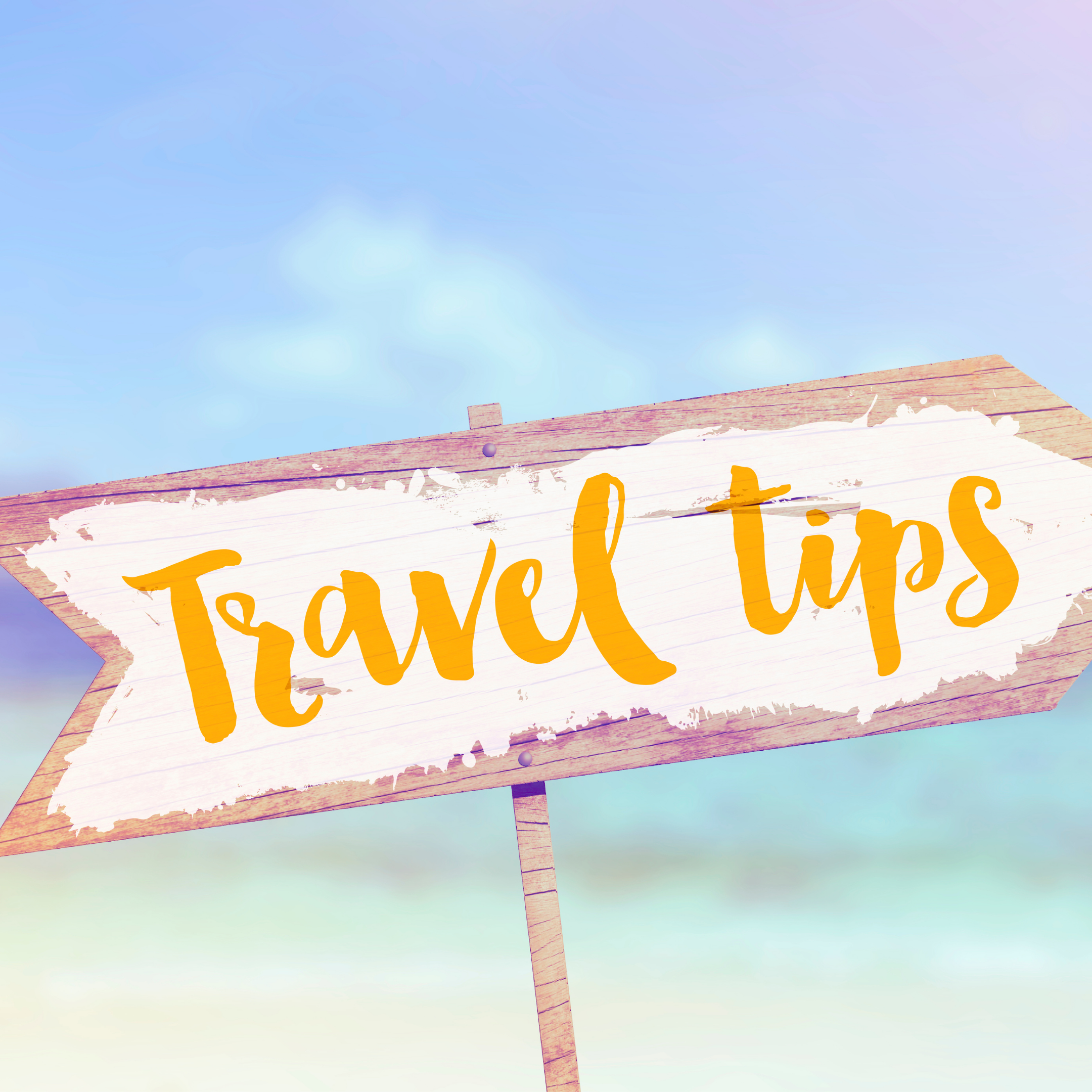 Wooden sign in front of beach scene with travel tips written on the sign